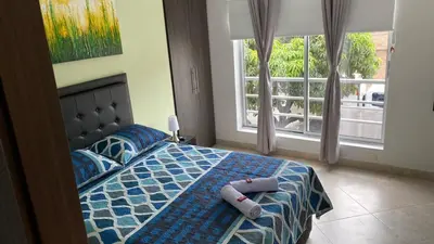 a bedroom with a bed with a blue comforter and a window at Amoblado laureles San Joaquín in Medellín