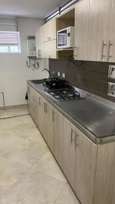 a kitchen with wooden cabinets and a stove top oven at Amoblado laureles San Joaquín in Medellín