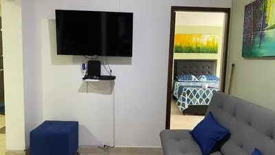 a living room with a couch and a television on a wall at Amoblado laureles San Joaquín in Medellín