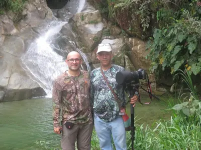 two men standing in front of a waterfall with a camera at La Posada de las Aves in San Rafael
