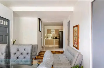 a living room with two gray couches and a kitchen at Hermosa Habitación in Medellín