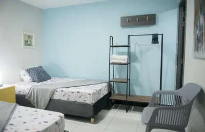 a small room with two beds and a chair at Casa Tangara Café y Hospedaje in Medellín