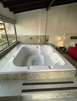 a large bath tub in a room with a red couch at Hotel Ofix in Medellín