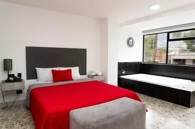 a bedroom with a red bed and a large window at Hotel Ofix in Medellín