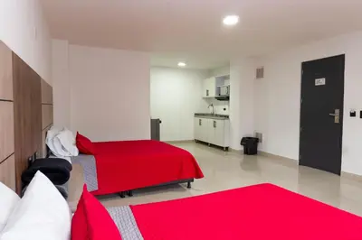 a bedroom with two beds and a red blanket at Hotel Ofix in Medellín