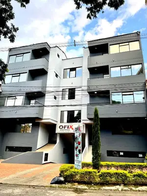 a white building with a sign in front of it at Hotel Ofix in Medellín