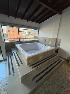 a large bath tub in a room with a window at Hotel Ofix in Medellín