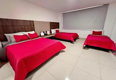 two beds in a room with red sheets and red pillows at Hotel Ofix in Medellín