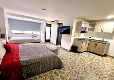 a hotel room with a bed and a kitchen at Hotel Ofix in Medellín