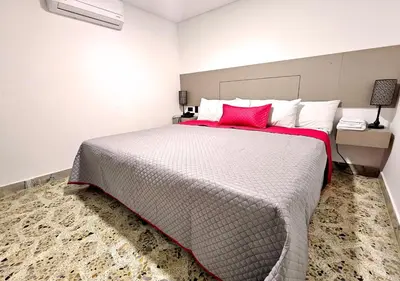 a bedroom with a large bed with a red pillow at Hotel Ofix in Medellín