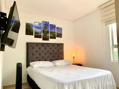a bedroom with a bed with four pictures on the wall at Piso26 Beautifull Apartment and Parking in Sabaneta
