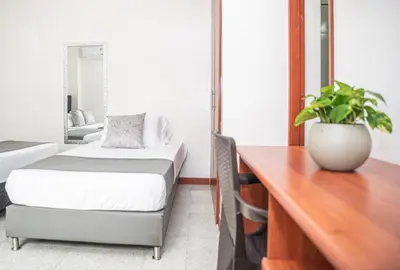 a bedroom with a desk and a bed and a plant at Hotel Villa Park Real in Medellín