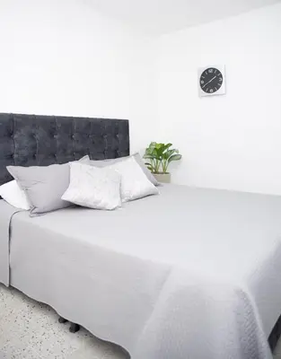 a white bed with a black headboard and white pillows at Hotel Villa Park Real in Medellín