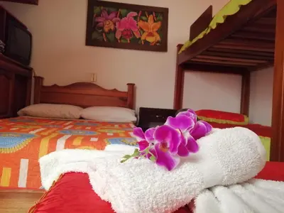 a bed with towels and a purple flower on it at Las Orquídeas Jardín Casa Hotel in Jardin