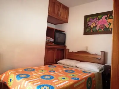 a bedroom with a bed and a tv on the wall at Las Orquídeas Jardín Casa Hotel in Jardin