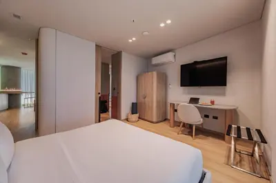 a bedroom with a bed and a desk and a tv at Seissta Medellín in Medellín