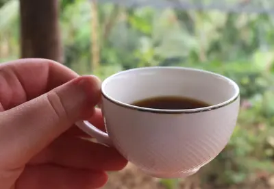 a person is holding a cup of coffee at hospedaje rural finca cafetera La Maloka in Jardin