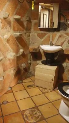 a bathroom with a sink and a stone wall at hospedaje rural finca cafetera La Maloka in Jardin