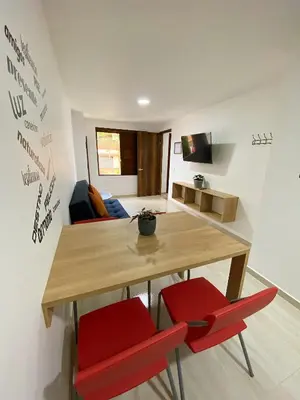 a dining room with a wooden table and two red chairs at Jardín de Primavera Apartamentos in Jardin