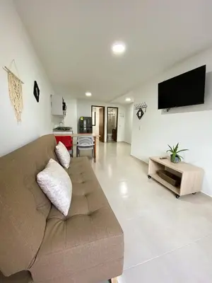 a living room with a brown couch and a flat screen tv at Jardín de Primavera Apartamentos in Jardin