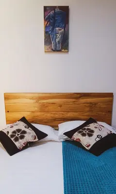 a bed with a wooden headboard and two pillows at Famy Hostal Nardo's in Jardin