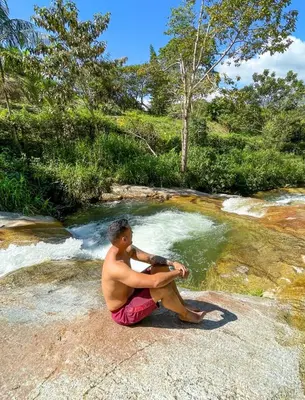 a man sitting on a rock in a pool of water at Pura vida alojamiento in Barbosa