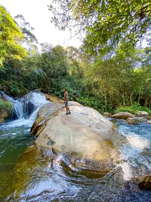 a man standing on a rock next to a waterfall at Pura vida alojamiento in Barbosa