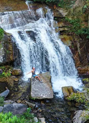 a person sitting on a rock in front of a waterfall at Pura vida alojamiento in Barbosa