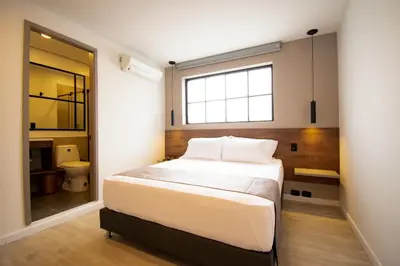 a bedroom with a large bed and a bathroom at Fence by Bernalo Hotels in Medellín