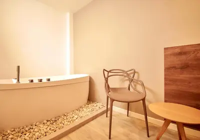 a bathroom with a tub and a chair and a table at Fence by Bernalo Hotels in Medellín