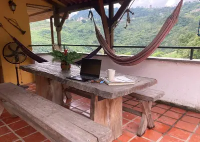 a laptop sitting on a wooden table with a bench at Mirador de los Vientos in Manizales