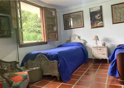 a bedroom with a bed with blue sheets and a window at Mirador de los Vientos in Manizales
