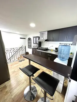 a kitchen with a table and two stools in it at Acogedor apto en Sonsón in Sonsón
