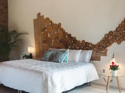 a bedroom with a large white bed with a wooden headboard at Hotel PIA Colombia in Marinilla