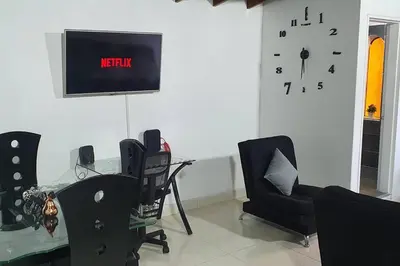 a room with a table and chairs and a clock on the wall at amplio apartamento en envigado in Envigado