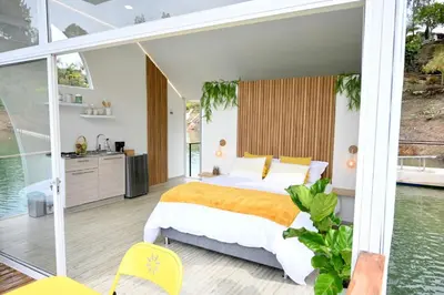 a bedroom with a large bed and a balcony at Casa Flotante La Trinidad in Guatapé