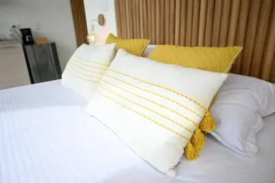 a white bed with yellow and white pillows on it at Casa Flotante La Trinidad in Guatapé