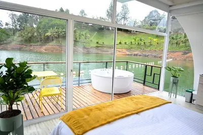 a bedroom with a tub and a large window at Casa Flotante La Trinidad in Guatapé