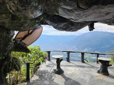 a person sitting on the ledge of a rock formation at Cabaña Parque Arvi vista panorámica in Medellín