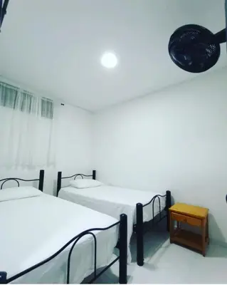 a white room with two beds and a table at Casa Vacacional in Mariquita