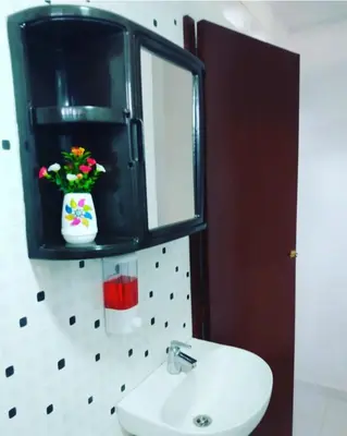 a bathroom with a sink and a mirror and a vase with flowers at Casa Vacacional in Mariquita