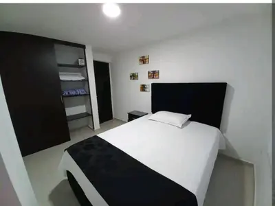 a bedroom with a white bed with a black headboard at Apartamento amoblado en la Francia in Manizales