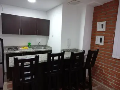 a kitchen with a counter with chairs and a sink at Apartamento amoblado en la Francia in Manizales