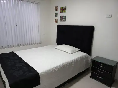 a bedroom with a bed with a black headboard and a night stand at Apartamento amoblado en la Francia in Manizales