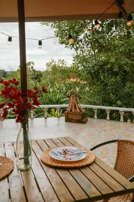 a table with a plate and a vase of flowers on it at Cabañas con jacuzzi y chimenea - Casa Floral, Marinilla in Marinilla