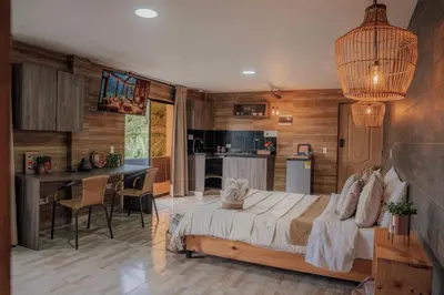 a bedroom with a large bed and a kitchen at Cabañas con jacuzzi y chimenea - Casa Floral, Marinilla in Marinilla