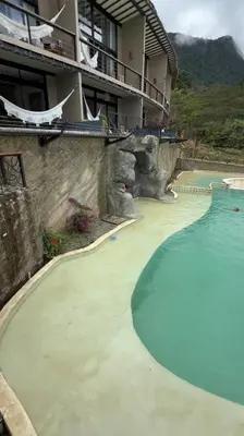 a swimming pool in front of a building with a house at Cerro Tusa Springs in Venecia
