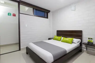 a bedroom with a bed with two green pillows at Ayenda 1254 Mi Colombia in Medellín
