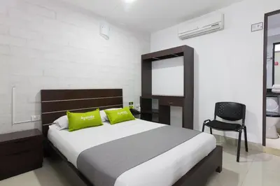 a bedroom with a bed with green pillows and a chair at Ayenda 1254 Mi Colombia in Medellín