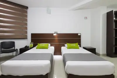 two beds in a hotel room with green pillows at Ayenda 1254 Mi Colombia in Medellín